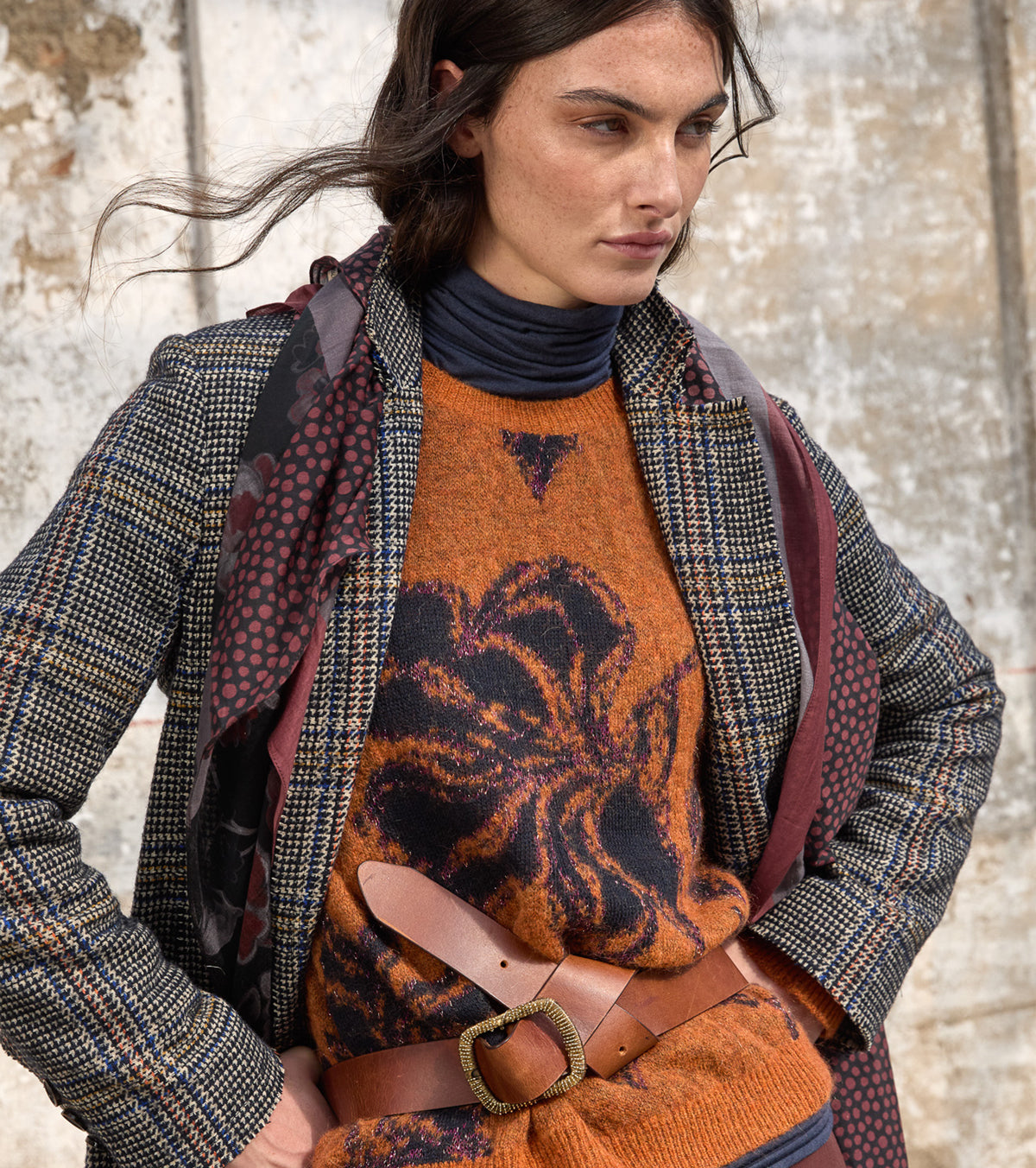 Look autunno inverno 2026/27 con maglia arancio lavorata, blazer check e pantalone marrone
